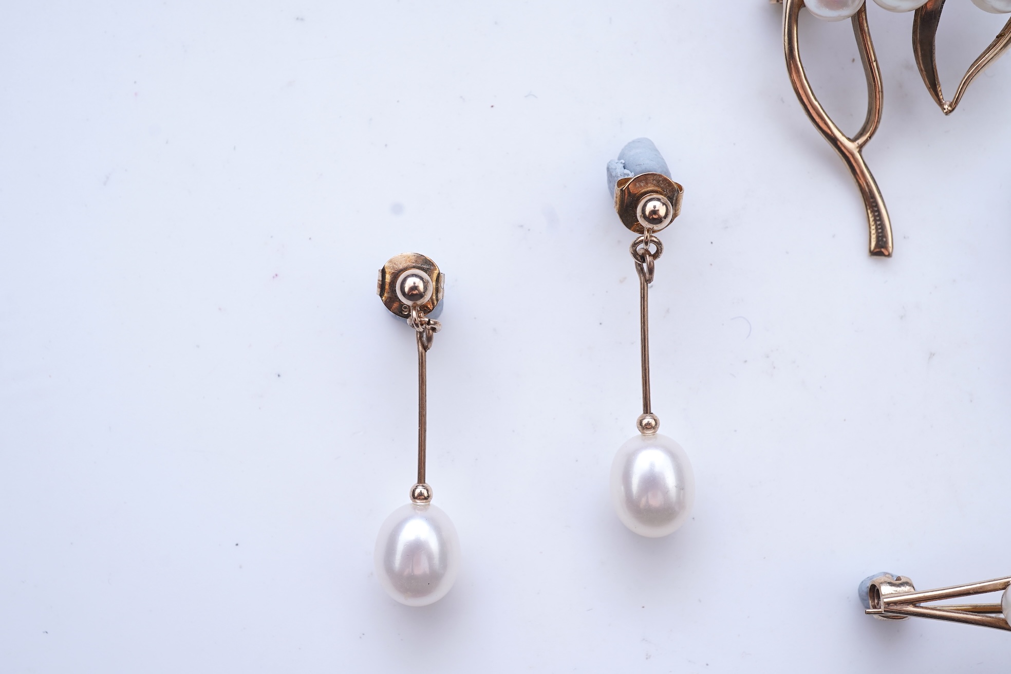 A group of cultured pearl jewels, comprising: two pairs of cultured pearl drop earrings, longest 3cm, mounted in gold; and two cultured pearl brooches mounted in 9ct gold, longest 4.1cm, British hallmarks, combined gross
